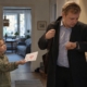 Dziewczynka w przedpokoju podaje laurkę tacie, który zakłada płaszcz i patrzy na zegarek